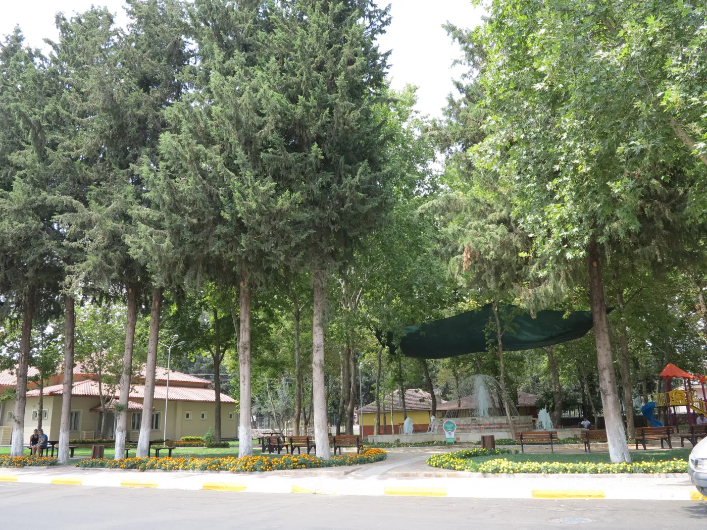 Varsak parkında ağaçlar, yürüyüş alanı ve çeşme